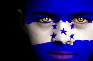 Portrait of a boy with the flag of Honduras painted on his face.